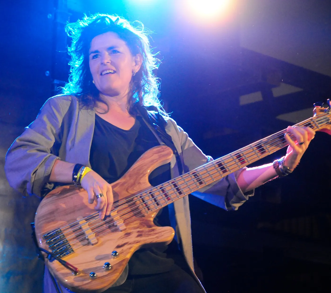 Lachende bassiste met een vijfsnarige basgitaar in het tegenlicht